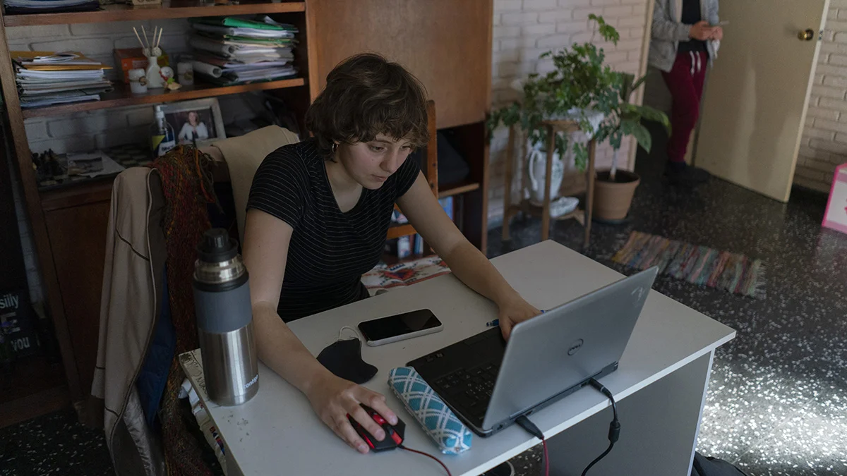 Frau sitzt am Schreibtisch und schaut auf einen Computer.